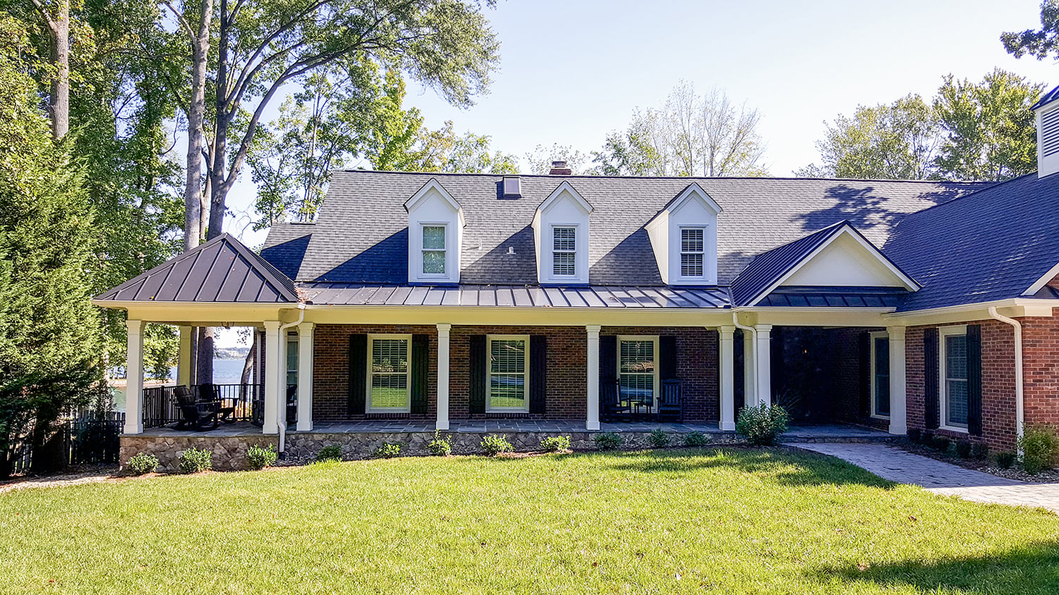 Front exterior of the Lake Norman home with flagstone porch, metal roof, and copper lanterns